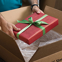 Man placing wrapped gift into a shipping box